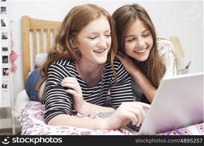 Two Teenage Girls In Bedroom Looking At Laptop