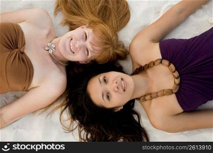 Two teenage girls lying on sand