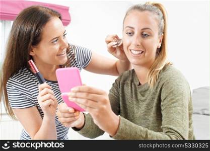 Two Teenage Girls Putting On Make Up In Bedroom