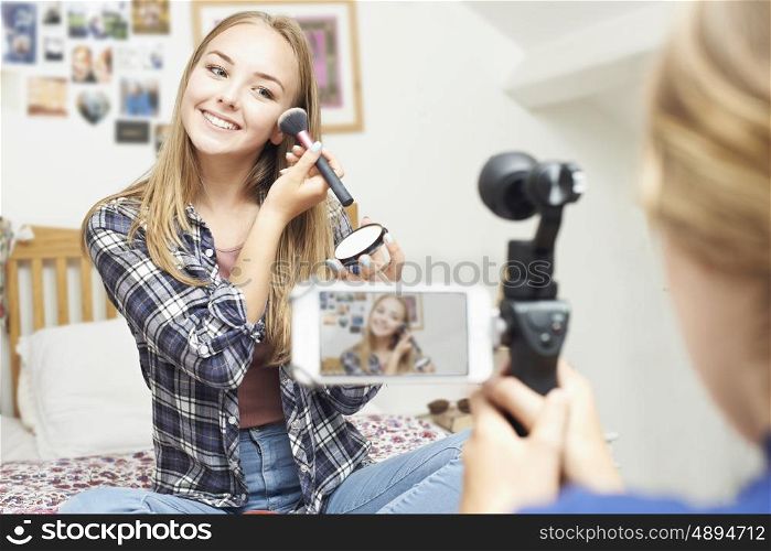 Two Teenage Girls Recording Beauty Blog In Bedroom