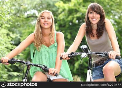 Two teenage girls riding bikes in the countryside