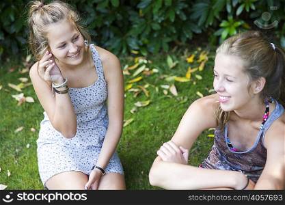 Two teenage girls sitting in garden