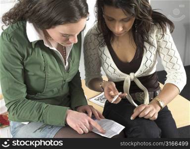 Two teenage girls sitting next to eachother and checking the pregnancy test