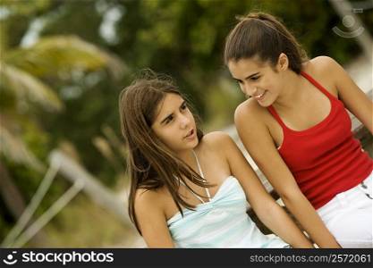 Two teenage girls sitting together smiling
