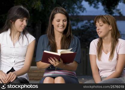 Two teenage girls sitting with their female teacher and smiling