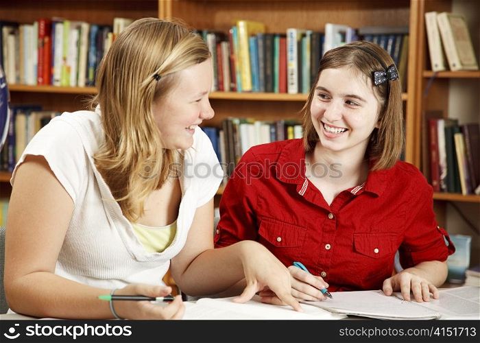 Two teenage girls studying together in the school library.