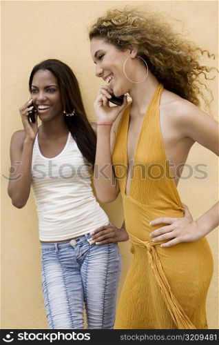 Two teenage girls talking on mobile phones