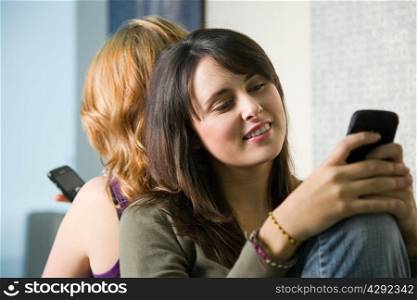 Two teenage girls texting on smartphones