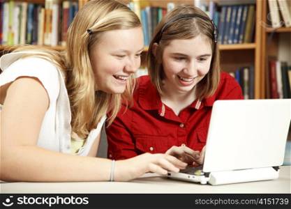 Two teenage girls using a netbook computer in the school library.