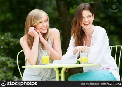 Two Teenage Girls Using Digital Tablet In Outdoor cafe