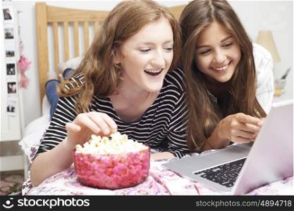 Two Teenage Girls Watching Movie On Laptop In Bedroom