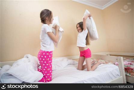 Two teenage sisters in pajamas having fun at pillow fighting
