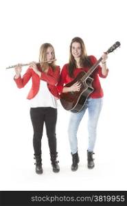 two teenage sisters play flute and guitar in studio with white background