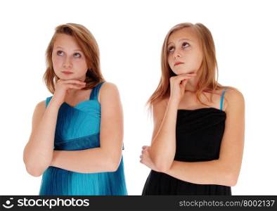 Two teenager girls in a black and blue dress with there hands under therechin, looking up, isolated foe white background.