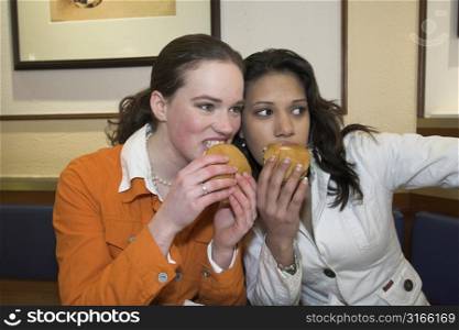 Two teenagers having a hamburger