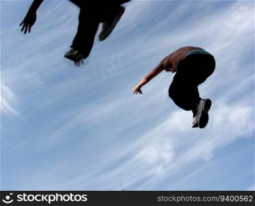 Two teenagers jumping with only the sky as the background