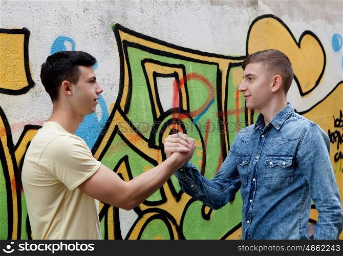 Two teenagers on the street greeting each other with graffiti background