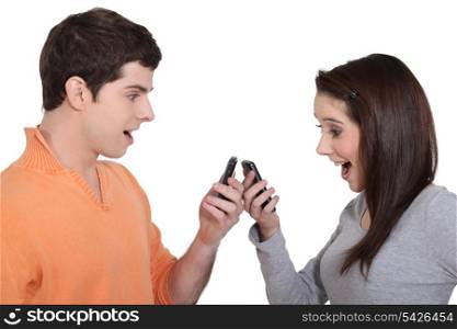 two teenagers playing with their cell phones