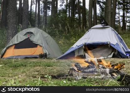 Two tents in forest. Fire on foreground