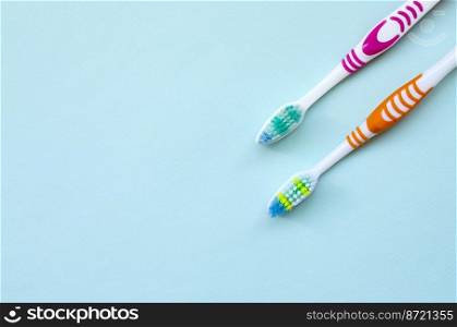 Two toothbrushes lie on a pastel blue background. Top view, flat lay. Minimal concept.. Two toothbrushes lie on a pastel blue background. Top view, flat lay. Minimal concept