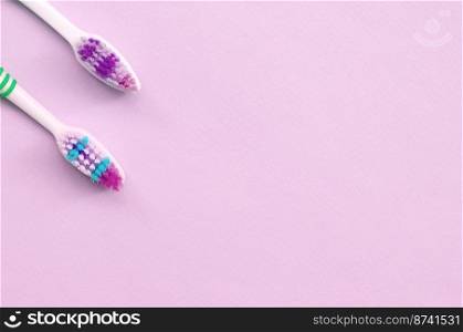 Two toothbrushes lie on a pastel pink background. Top view, flat lay. Minimal concept.. Two toothbrushes lie on a pastel pink background