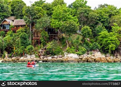 Two tourists are father and daughter travel by boat with a kayak in summer at front the resort on island of Ko Lipe enjoy the beautiful nature the sea in morning, Tarutao National Park, Satun, Thailand. Father and daughter travel by kayak at Ko Lipe, Thailand