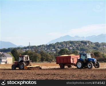 Two tractors working on field during the harvest of the corn