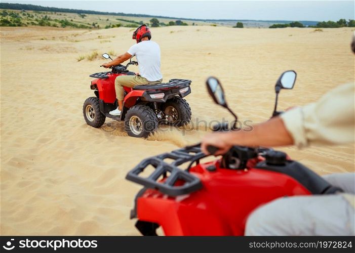 Two travelers in helmets, freedom atv riding in desert sands. Male persons on quad bikes, sandy race, dune safari in hot sunny day, 4x4 extreme adventure, quad-biking. Two travelers in helmets, atv riding in desert