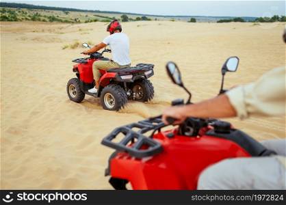 Two travelers in helmets, freedom atv riding in desert sands. Male persons on quad bikes, sandy race, dune safari in hot sunny day, 4x4 extreme adventure, quad-biking. Two travelers in helmets, atv riding in desert