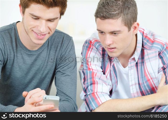 Two ttenage boys checking text message