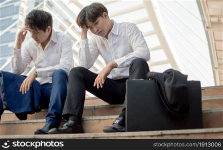 Two unemployed business men or workers sitting beside street and being sad after losing their jobs. Social Issue and Unemployment Concept.