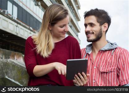 Two University students studying together using digital tablet at the building of university. Education concept
