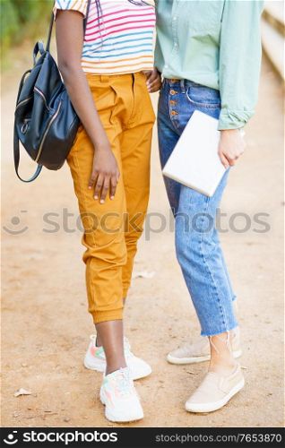Two unrecognizable multiethnic girls posing together with colorful casual clothing outdoors.. Two unrecognizable multiethnic girls posing together with colorful casual clothing