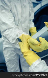 Two unrecognizable people with bacteriological protection suits putting on protective gloves. Young people putting on protective gloves