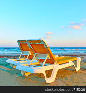 Two vacant deckchairs on a sandy beach