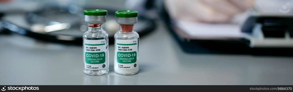 Two vials of coronavirus vaccine on a female doctor’s table