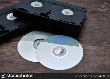 Two video cassettes isolated on a wooden background with cd's