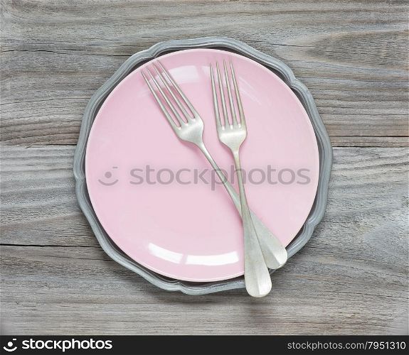 Two vintage fork on an empty pink plate