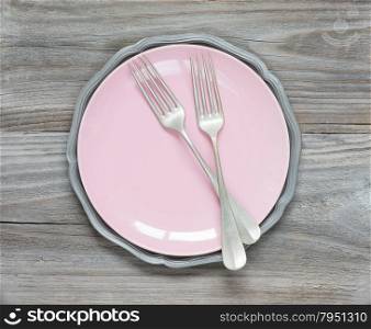 Two vintage fork on an empty pink plate