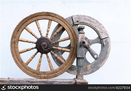Two vintage spinning wheels on white shabby wall