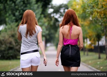 Two walking young woman with beautiful red hair