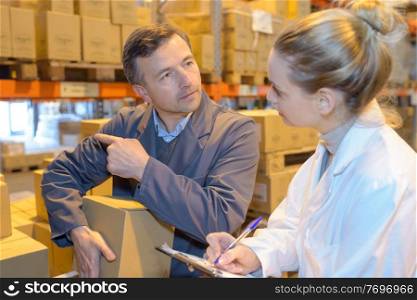 two warehouse managers checking inventory in a large warehouse