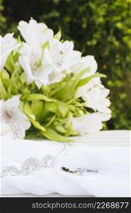 two wedding rings crown scarf with beautiful flower bouquet table