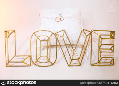 Two wedding rings on a white pillow close up with love. Two wedding rings on a white pillow close up