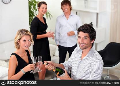 two well dressed couples drinking sparkling wine in a living room