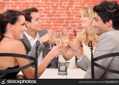 two well dressed couples toasting at the restaurant