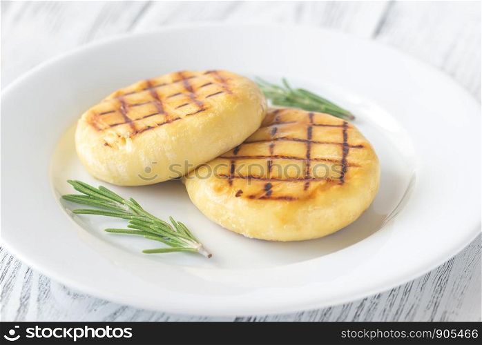 Two wheels of grilled cheese with fresh rosemary