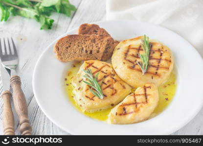 Two wheels of grilled cheese with fresh rosemary