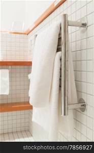 Two white bath towels hanging on a silver towel rack
