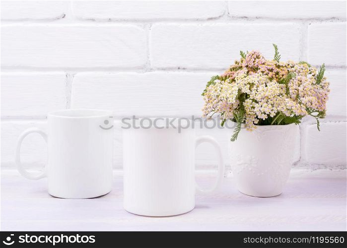 Two white coffee mug mockup with pink beige wild flowers in the vase. Empty mug mock up for design promotion.
